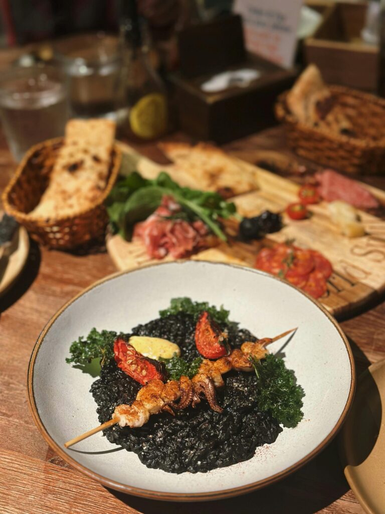 Delicious squid ink risotto served with skewered seafood and fresh vegetables in Vietnam.