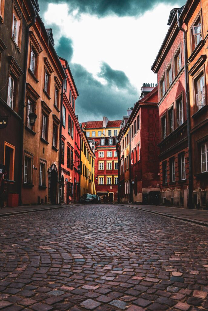 Dramatic view of cobblestone street in Warsaw's Old Town, showcasing colorful historic architecture.