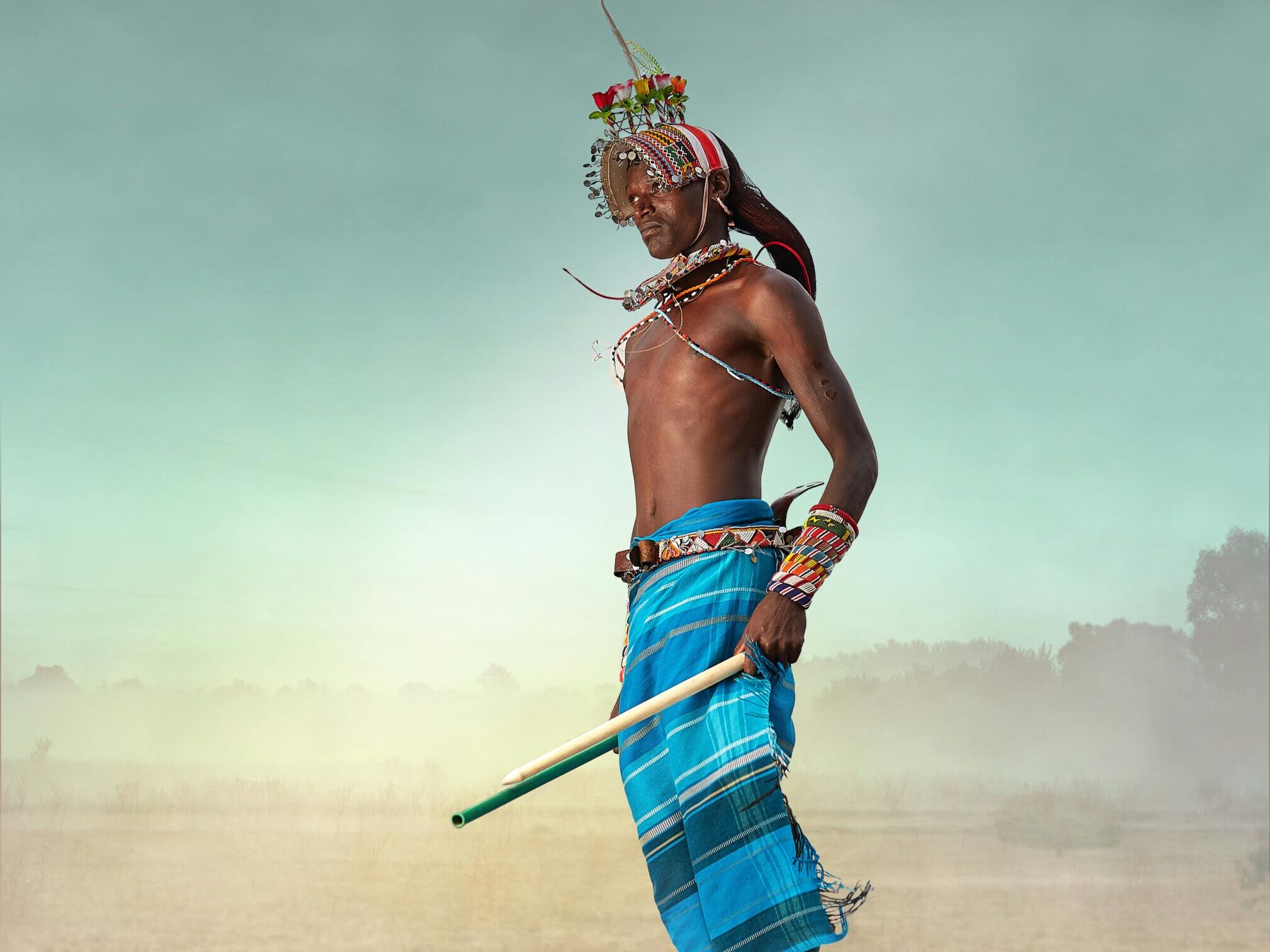A Maasai warrior in traditional attire jumps high, showcasing cultural dance in Kenya.