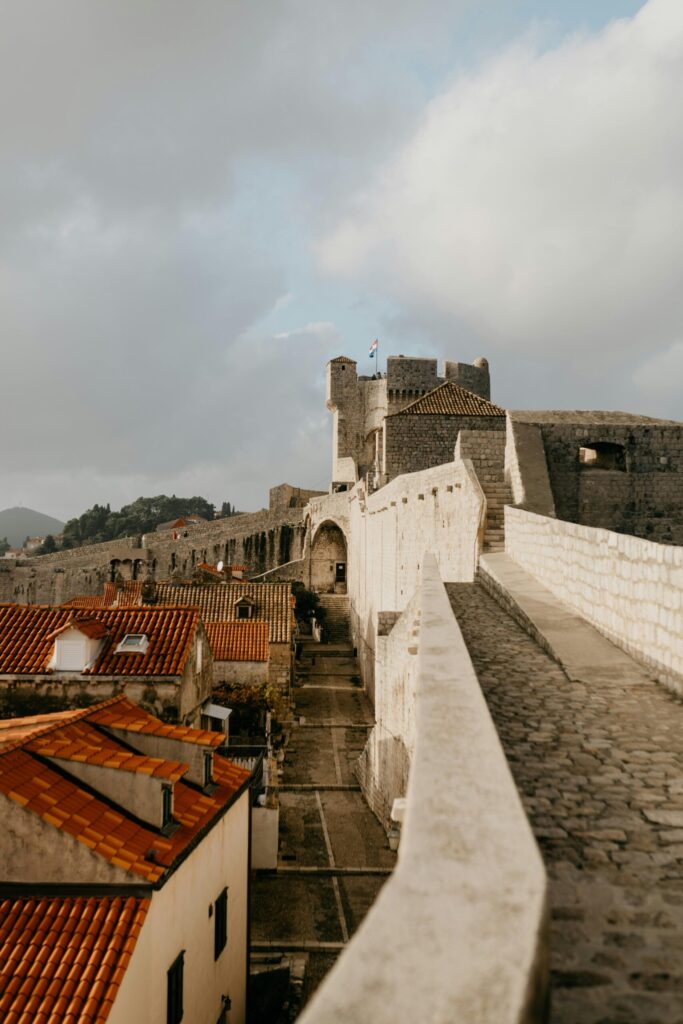 Explore the medieval charm of Dubrovnik's ancient city walls under a cloudy sky.
