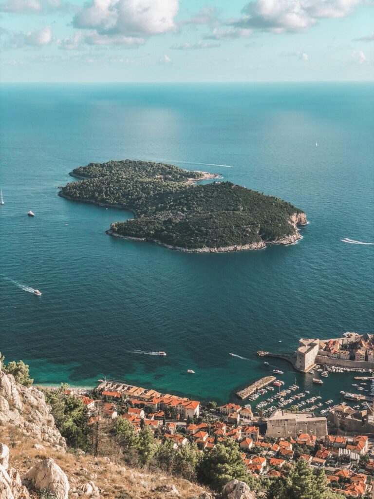 A breathtaking aerial view of a lush island and vibrant coastal city under a bright sky.